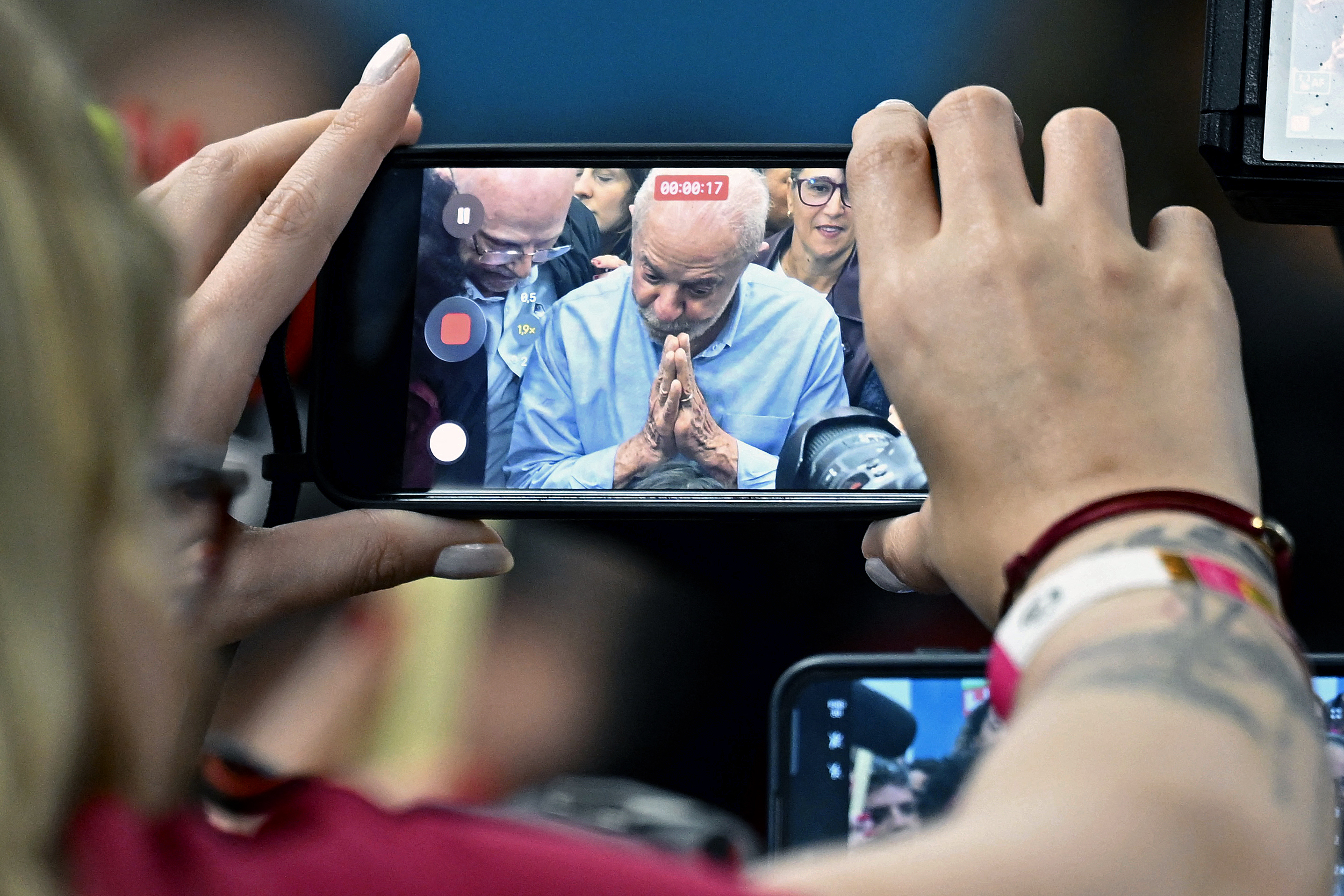 Brazil's President and re-election candidate Luiz Inacio Lula da Silva is seen on mobile phone and camera screens as he speaks during a meeting with current and newly elected lawmakers at a hotel in Brasilia on October 7, 2026. (Photo by Evaristo Sa / AFP)