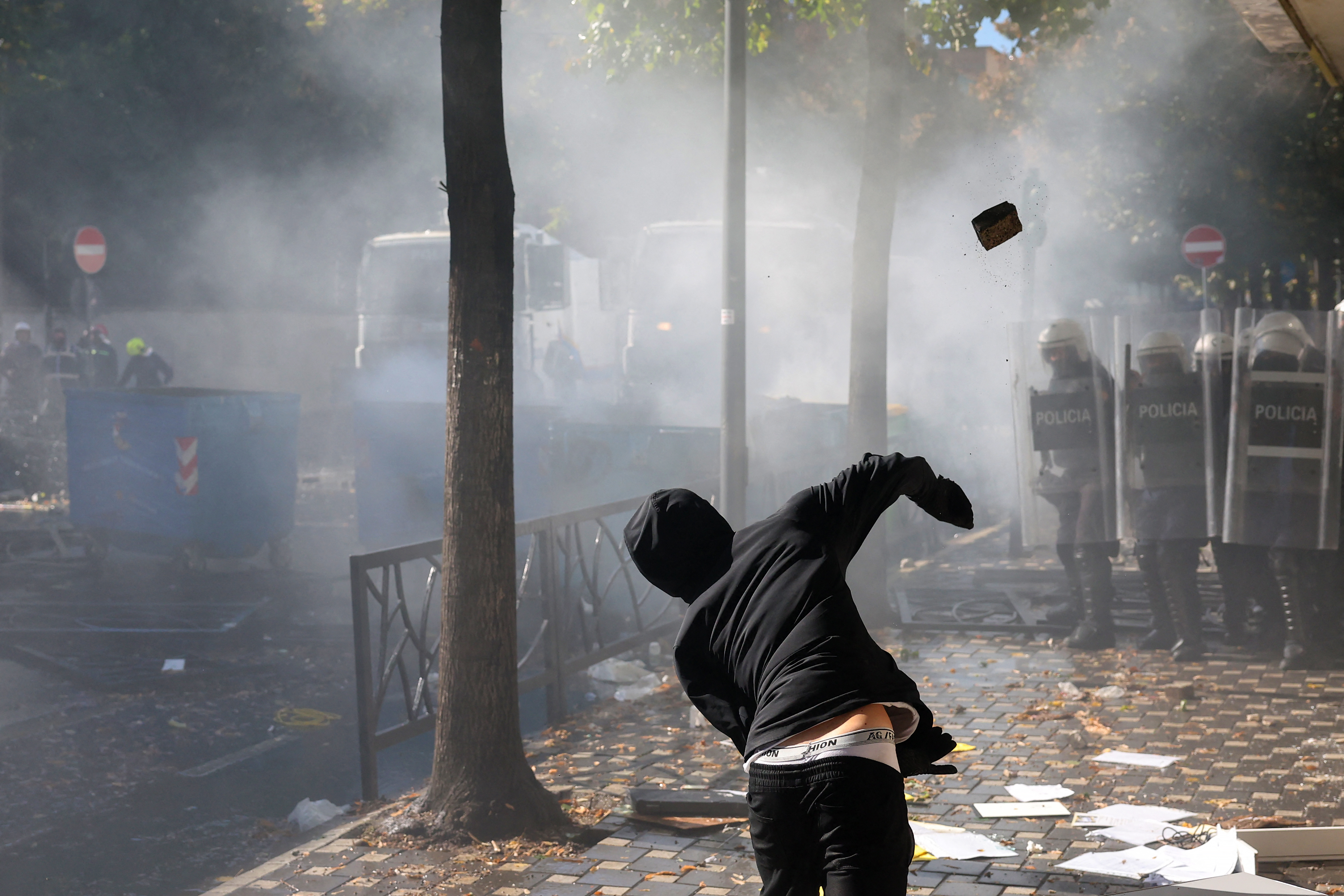 A protester throws a brick at police during clashes with riot police in central Tirana on October 14, 2026, as violence erupted for a second consecutive day during demonstrations demanding the resignation of Albanian Prime Minister and better education.