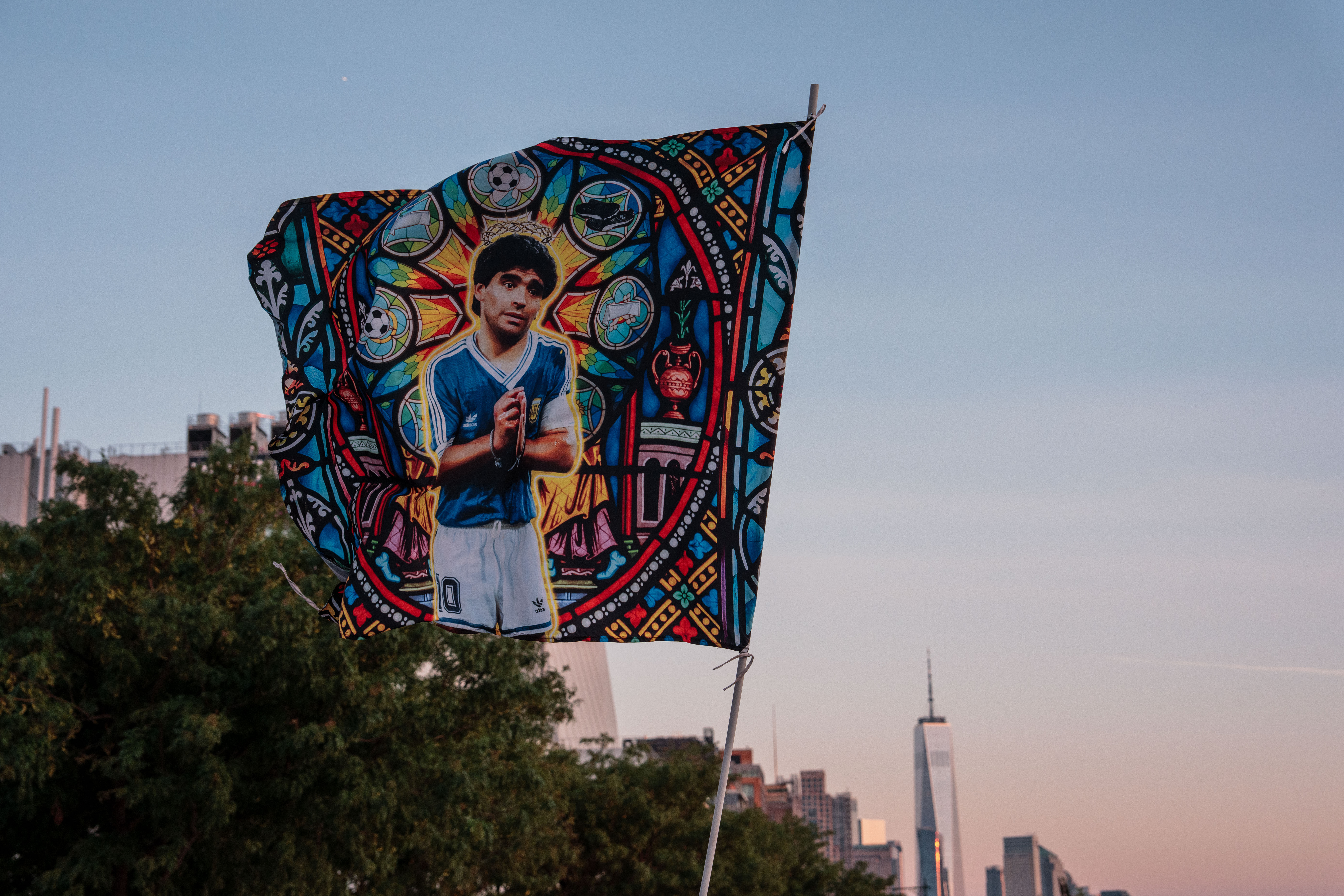 A Diego Maradona flag is held in the air by fans.