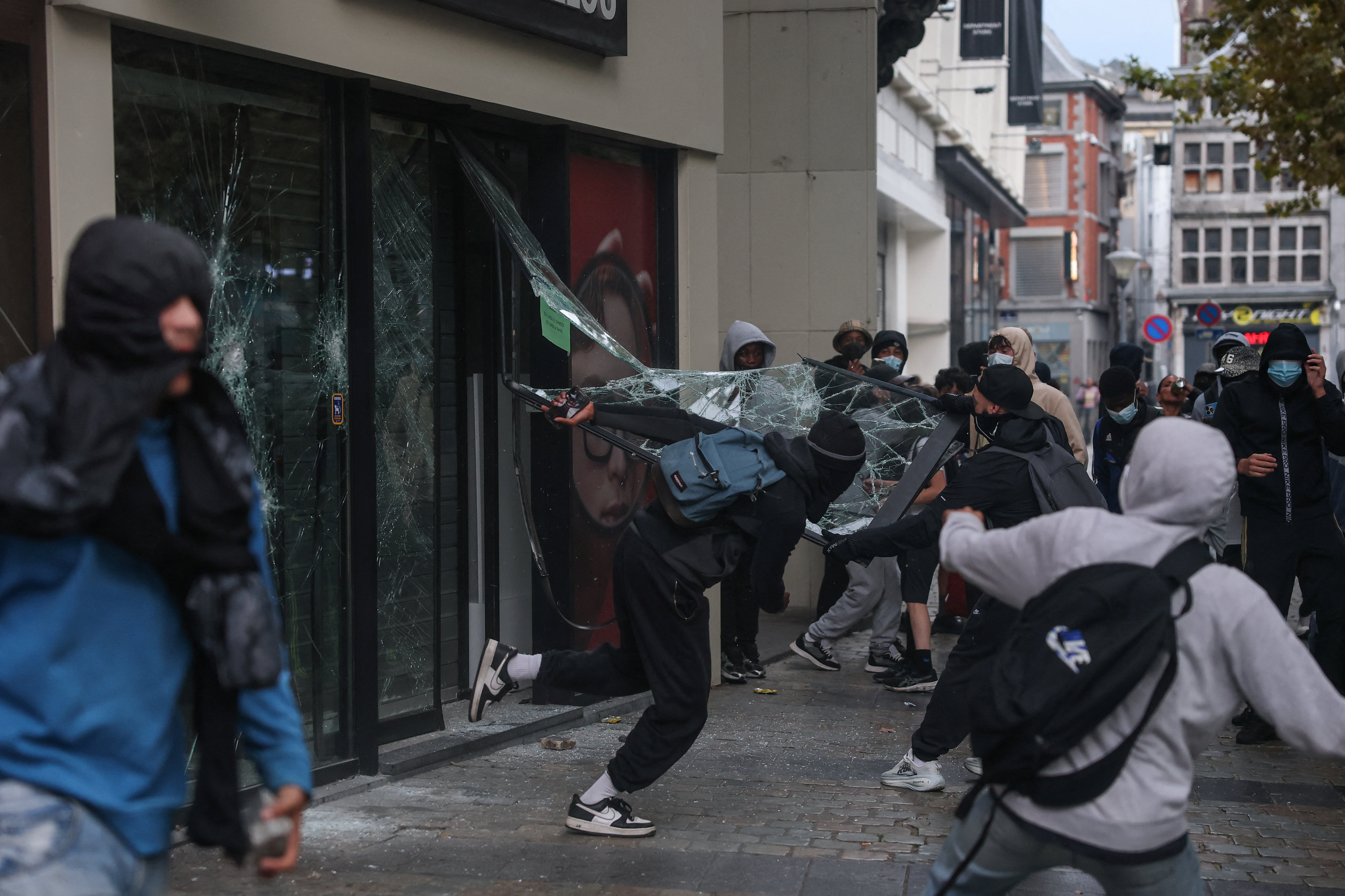 Demonstrators break the glass of a storefront, on the day of a spontaneous street protest of high school students against education reforms introduced by the Wallonia-Brussels Federation government and an increase in student fees, in Liege, Belgium, October 7, 2026. REUTERS/Stephanie Lecocq