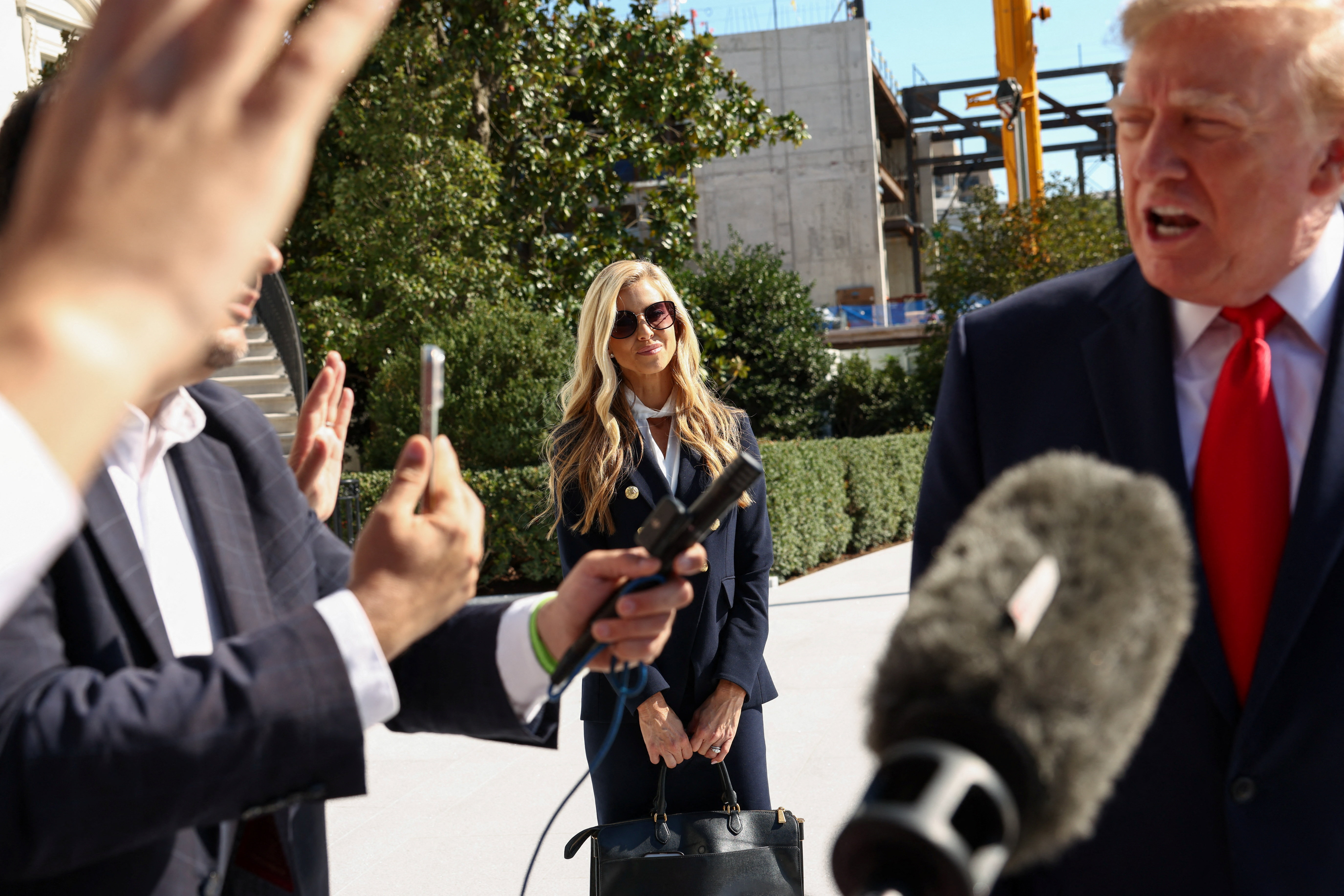 New White House Press Secretary Katie Zacharia listens to US President Donald Trump speaking to the media as he departs the White House in Washington, DC, US, October 13, 2026. REUTERS/Kevin Lamarque