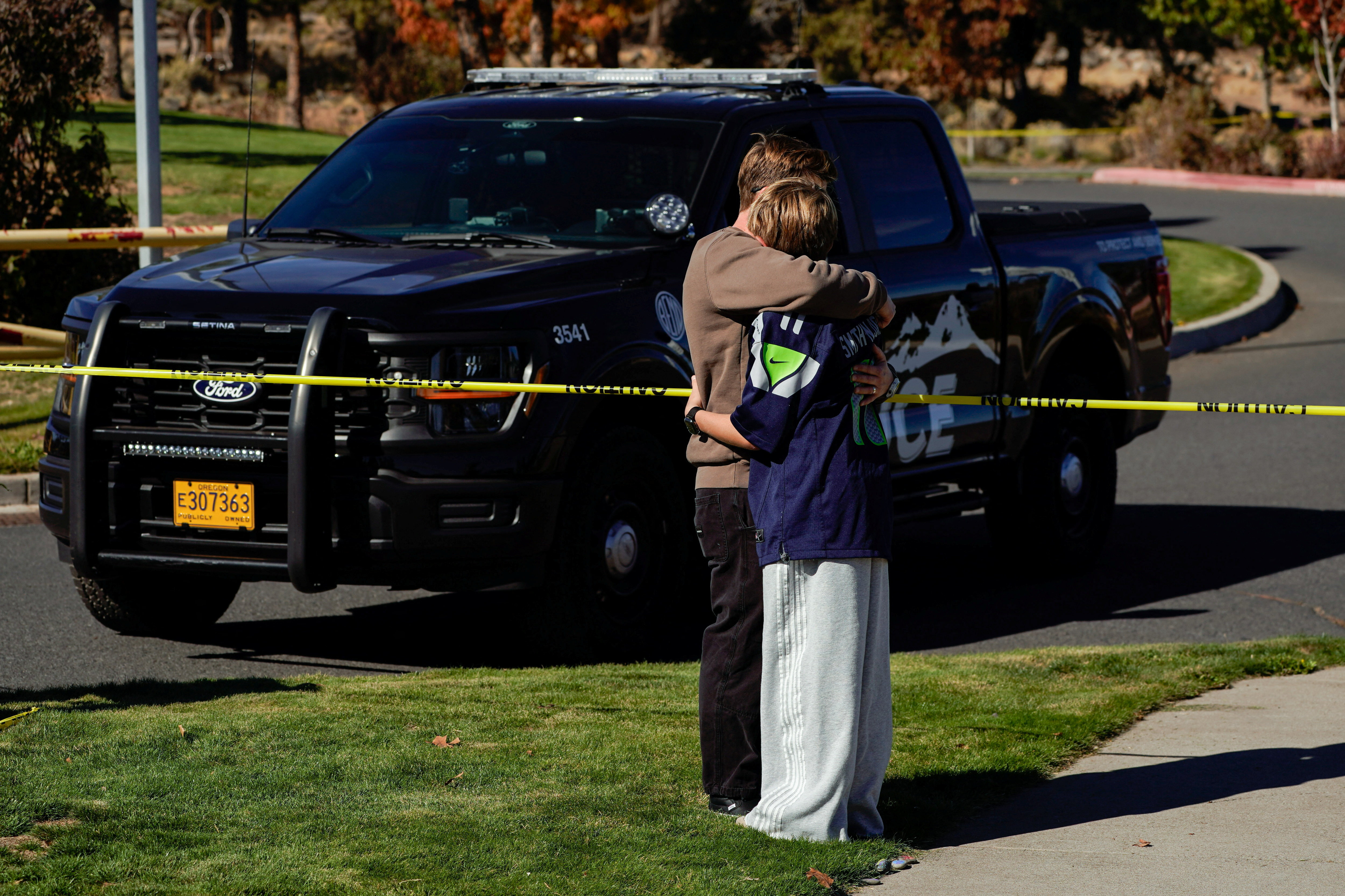 People mourn next to a cordoned-off area at Silver Rail Elementary School in Bend, Oregon, on October 16, 2026, the day after a shooting