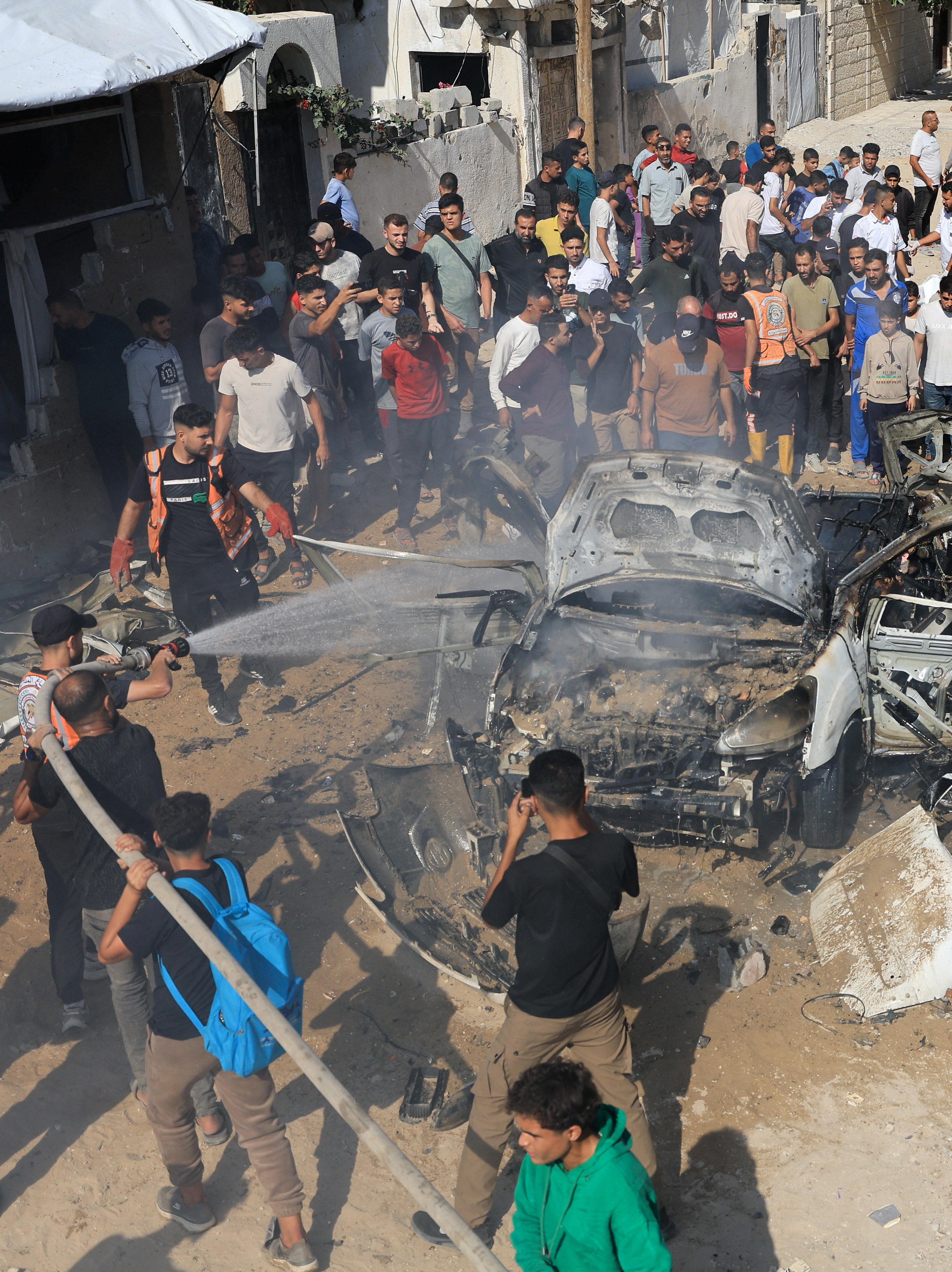 Palestinians spay a vehicle with water after it was hit by an Israeli strike, according to health officials, in Gaza City, October 22, 2026. REUTERS/Dawoud Abu Alkas