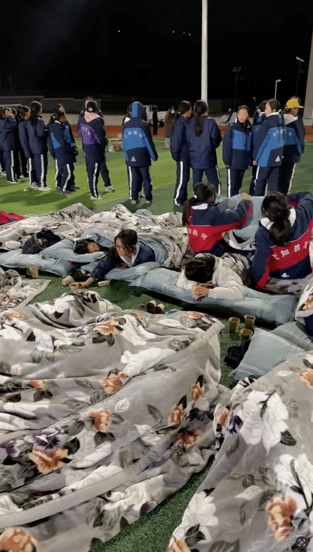 Students sleep on a playground following an earthquake in Nagqu, Tibet Autonomous Region, China in this screengrab taken from a social media video released October 23, 2026. SOCIAL MEDIA/via REUTERS THIS IMAGE HAS BEEN SUPPLIED BY A THIRD PARTY. NO RESALES. NO ARCHIVES. NEWS USE ONLY. VERIFICATION: -Buildings, stadium turf and lamp posts matched archive and satellite images -Exact time not verified but no older version found posted online before October 23 -Nagqu Emergency Management confirmed in a statement that magnitude 7.0 quake hit the city on the evening of October 22